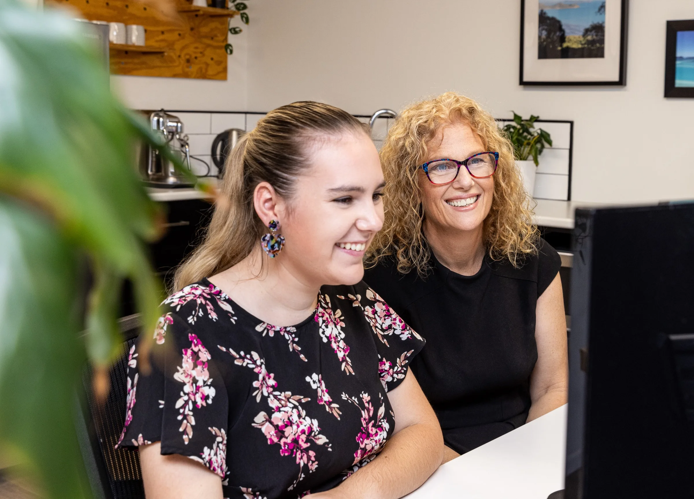 Two Ready Accounting team members smiling as they work through something at a desk